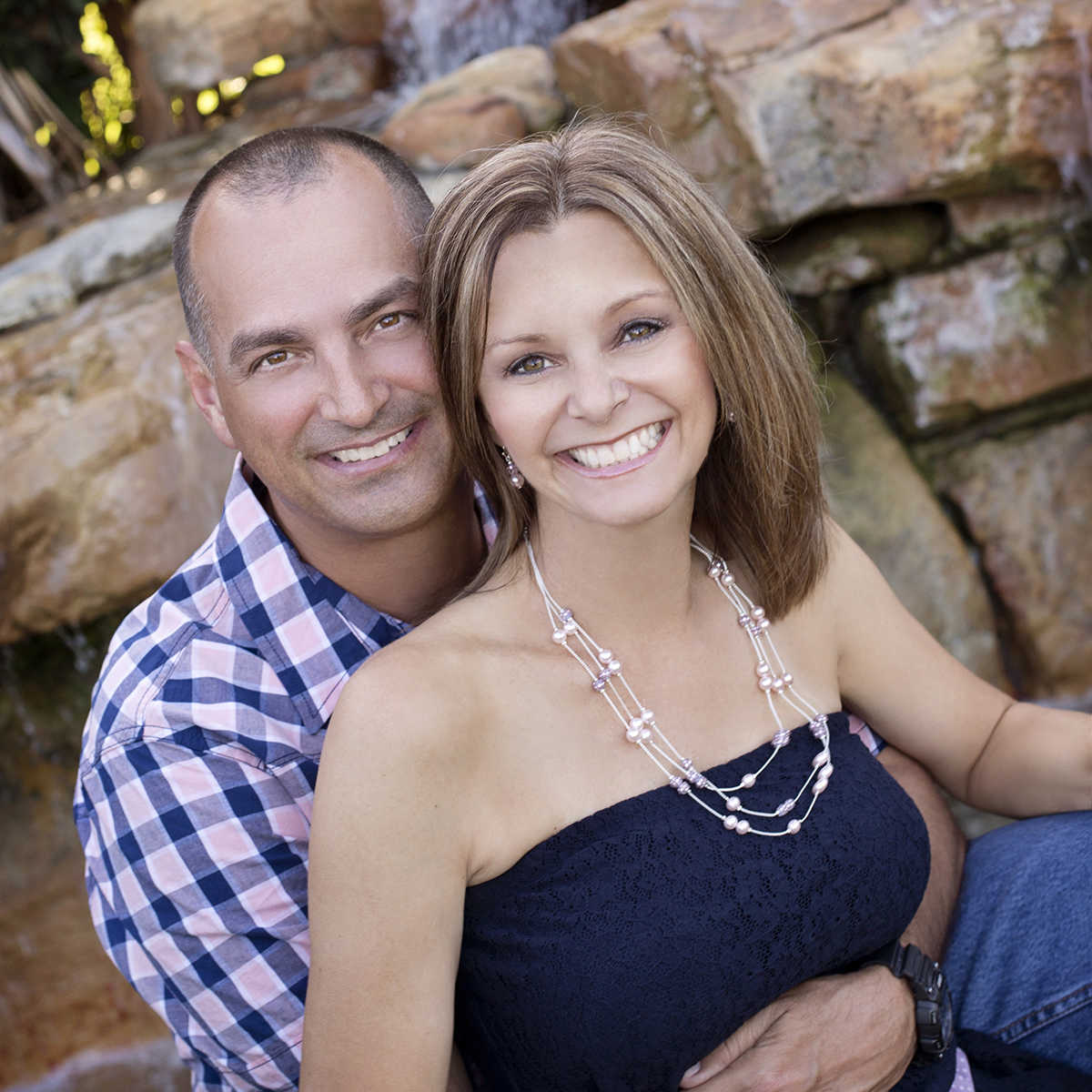 husband with arms wrapped around wife smiling