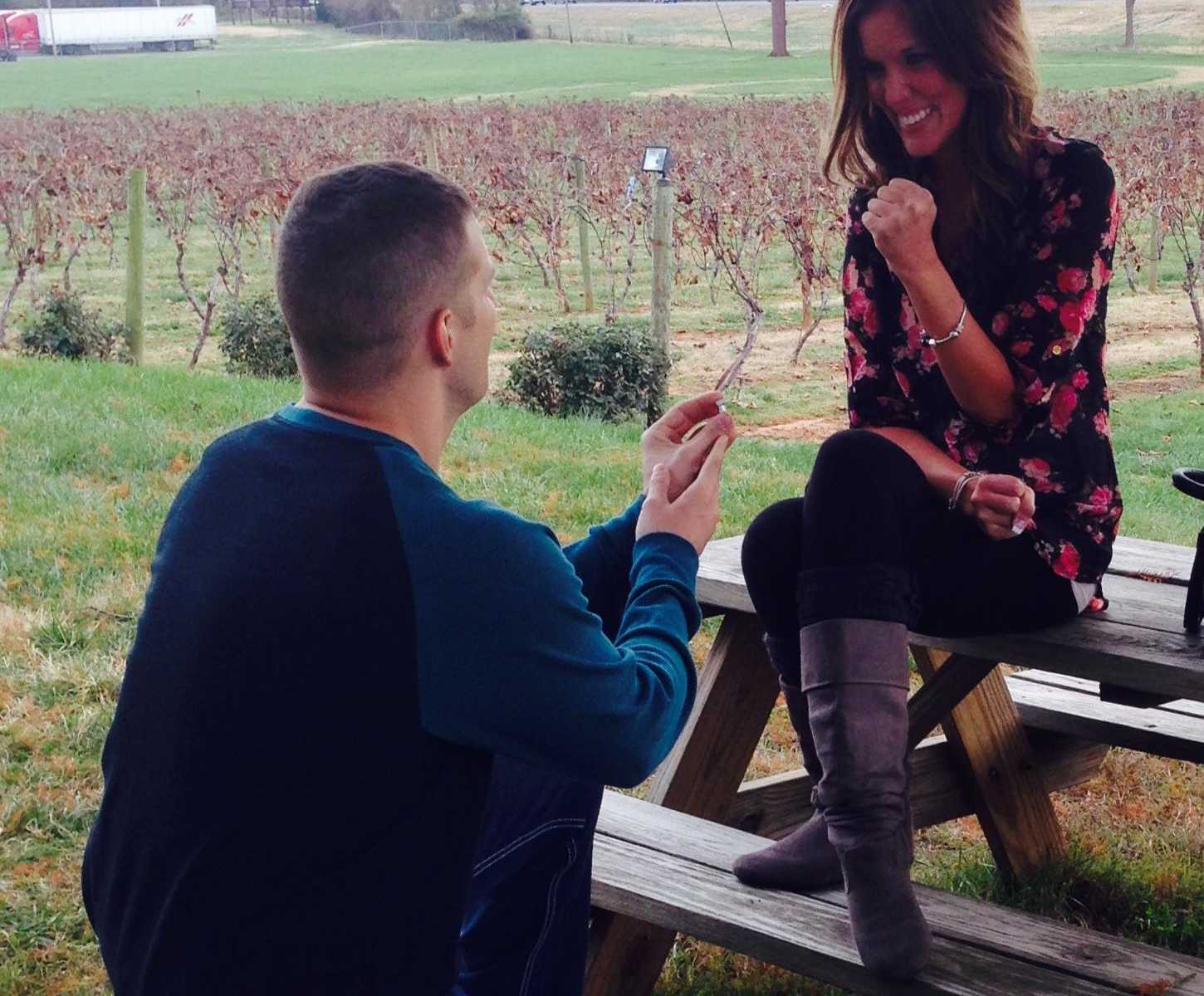 soldier proposes to girlfriend who is sitting on picnic table