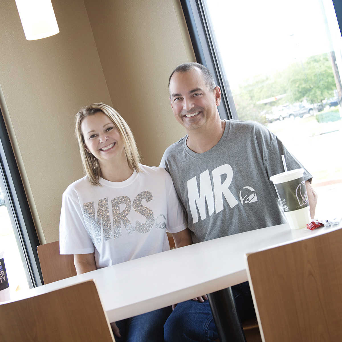 husband and wife sitting and smiling at taco bell table