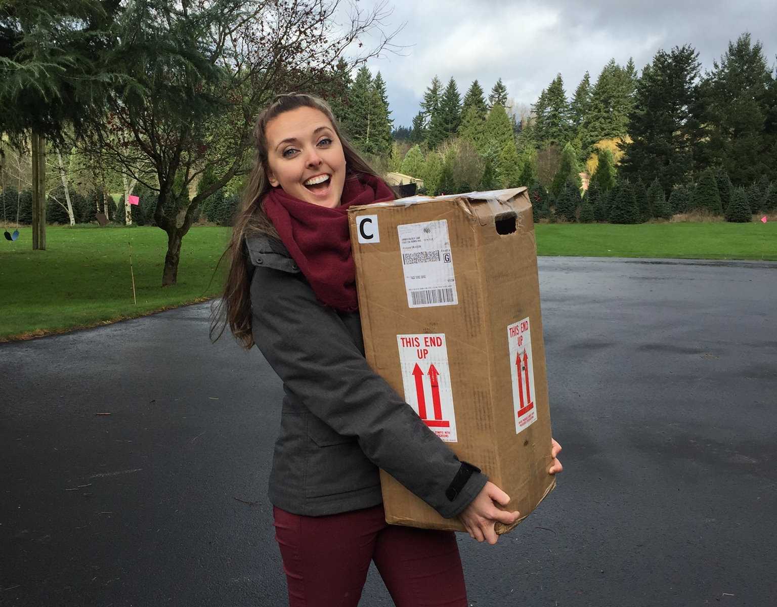 woman smiling holding a shipment box of embryos in a driveway