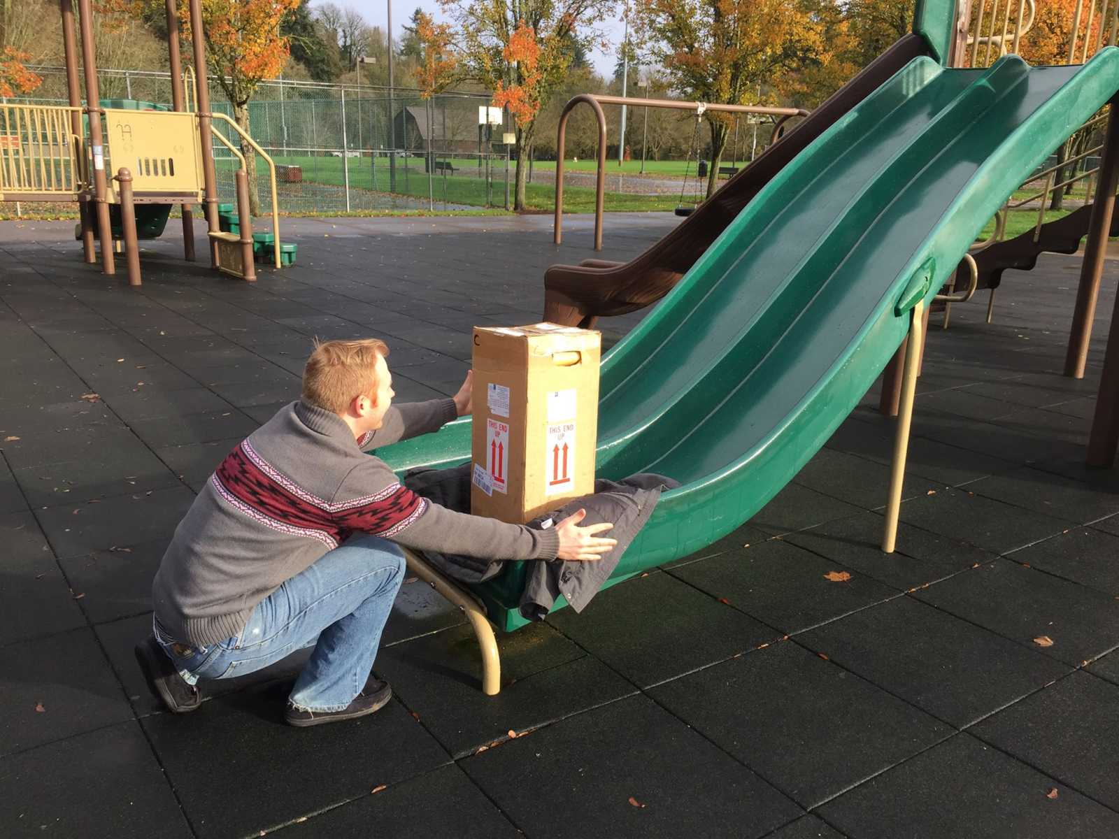 shipment box of embryos placed on a slide while a man crouches down at the end of the slide ready to catch it