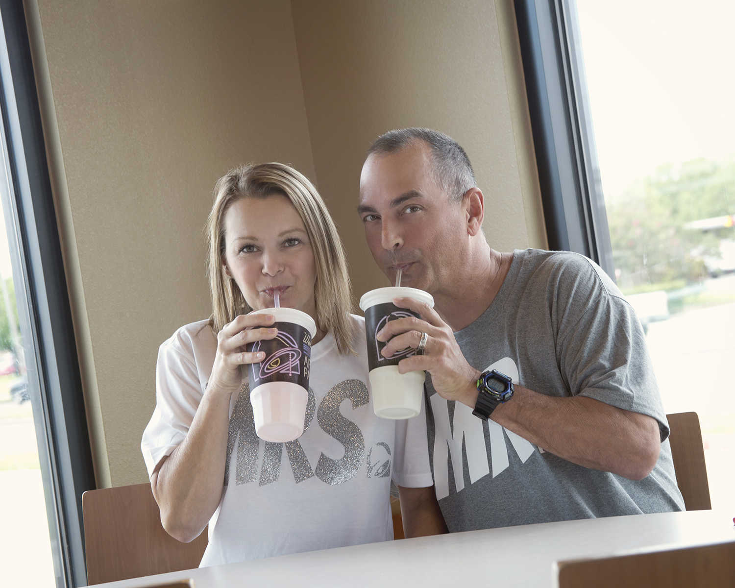 husband and wife holding up their cup and sipping out of straw