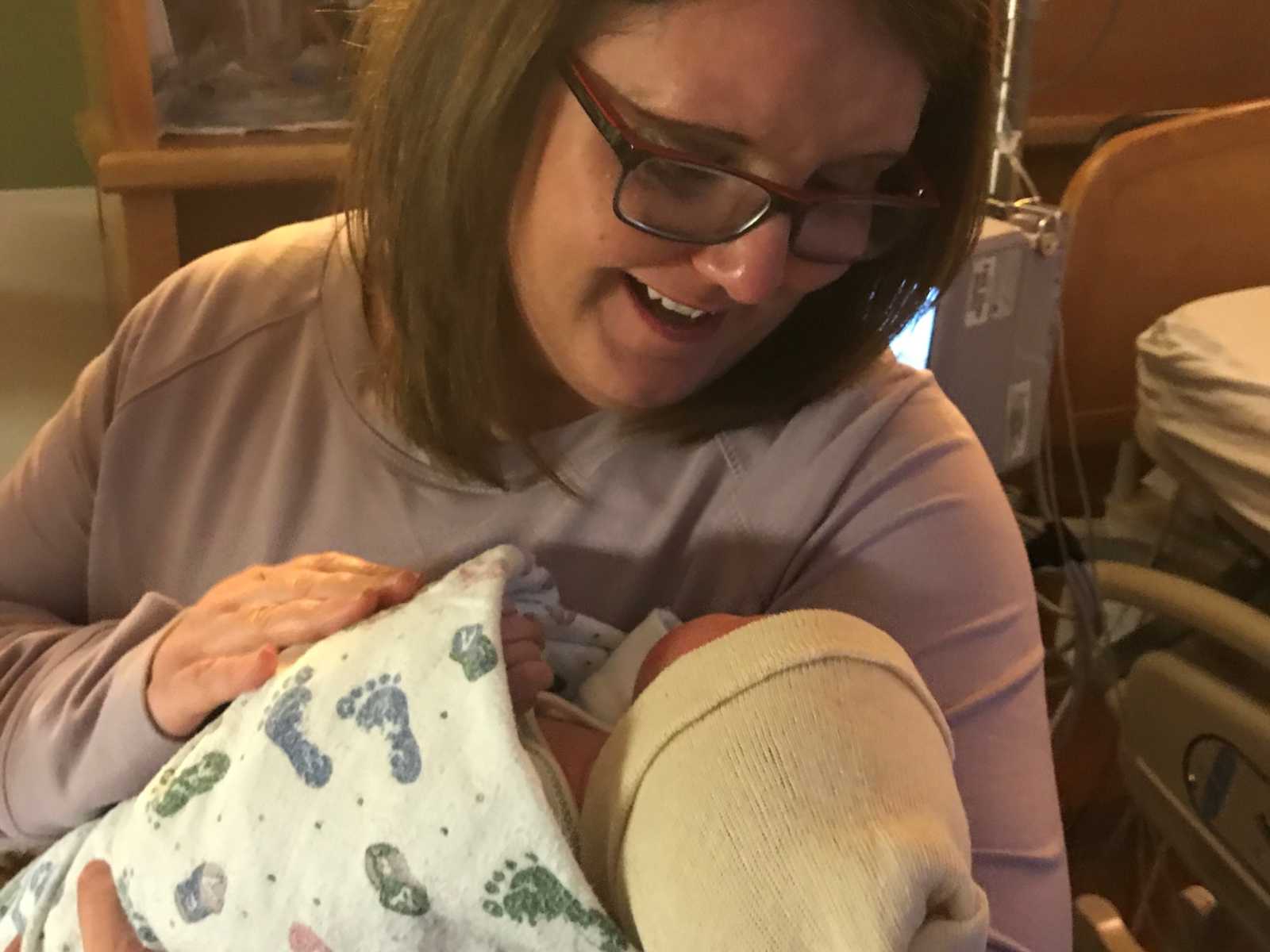 adoptive mom holds newborn daughter in hospital room