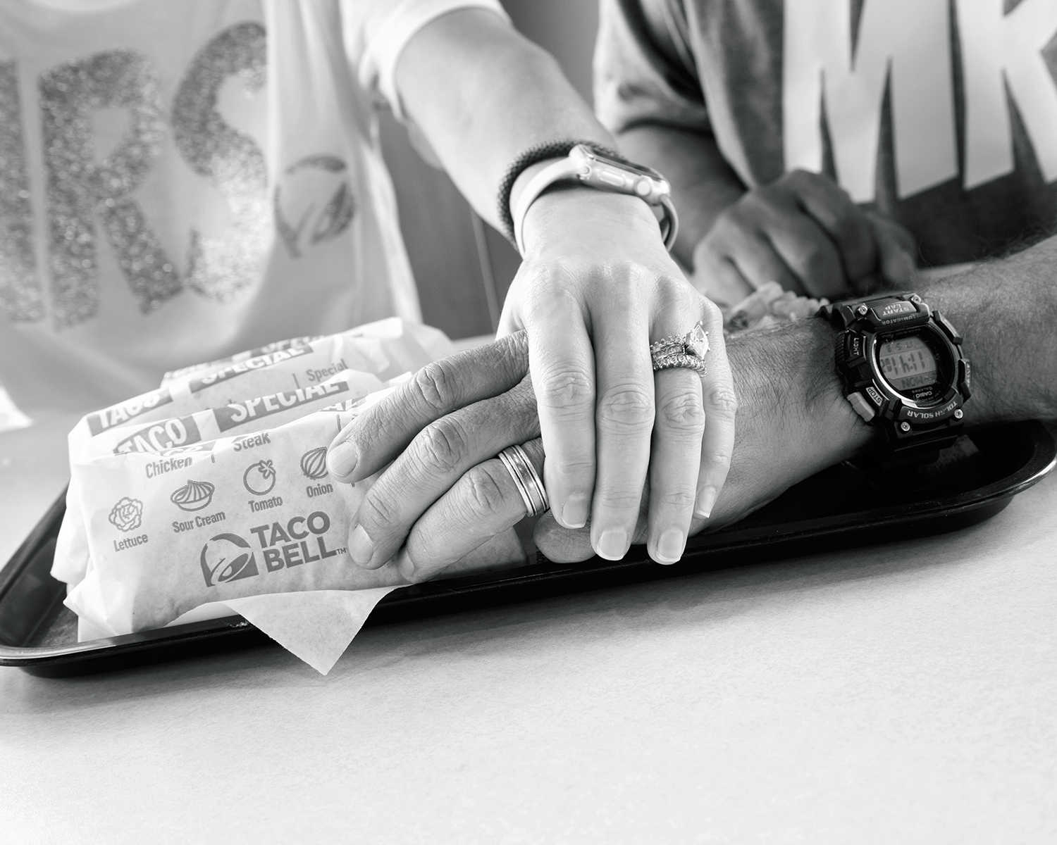 husband and wife hands are held on taco bell tray next to wrapped tacos