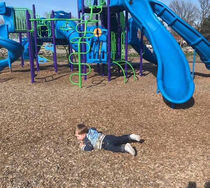 Toddler lies on his stomach on playground 