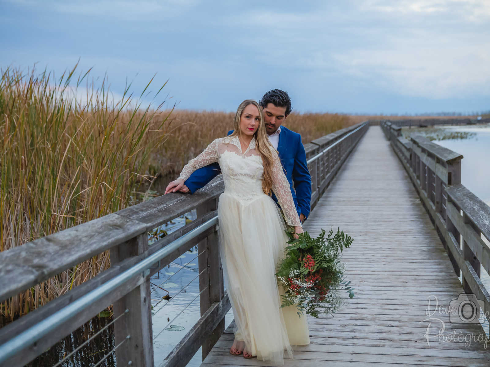 engaged couple posing on bridge that overlooks water 