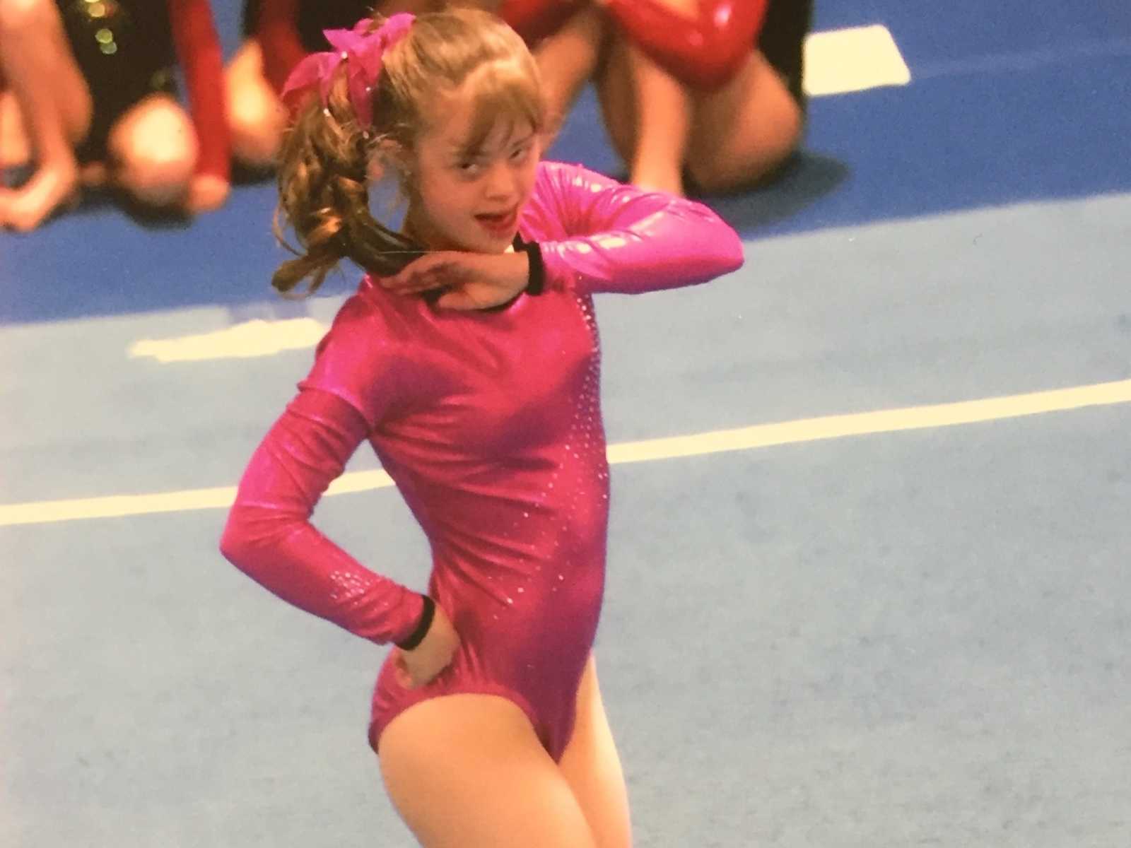 down syndrome girl with pink sparkly leotard and scrunchie does a floor routine