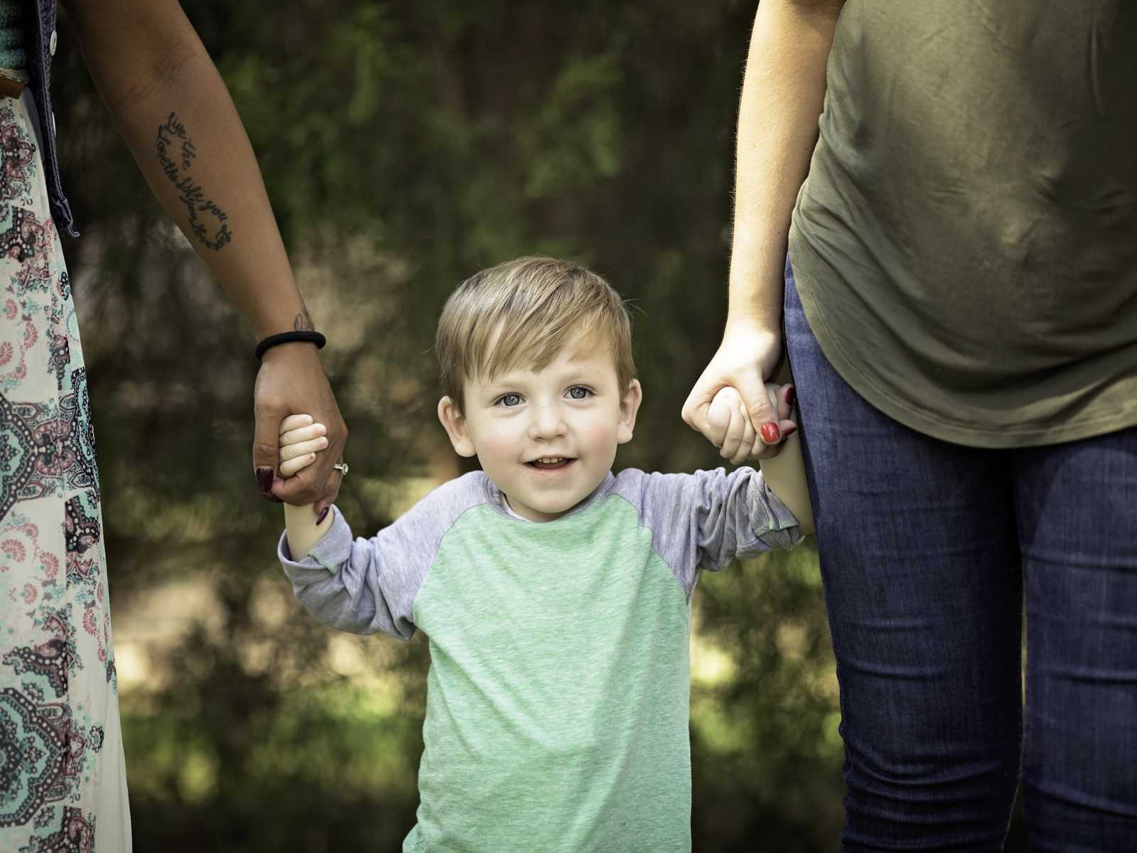 little boy with a new heart holds hands with his mother and mother of his heart donor