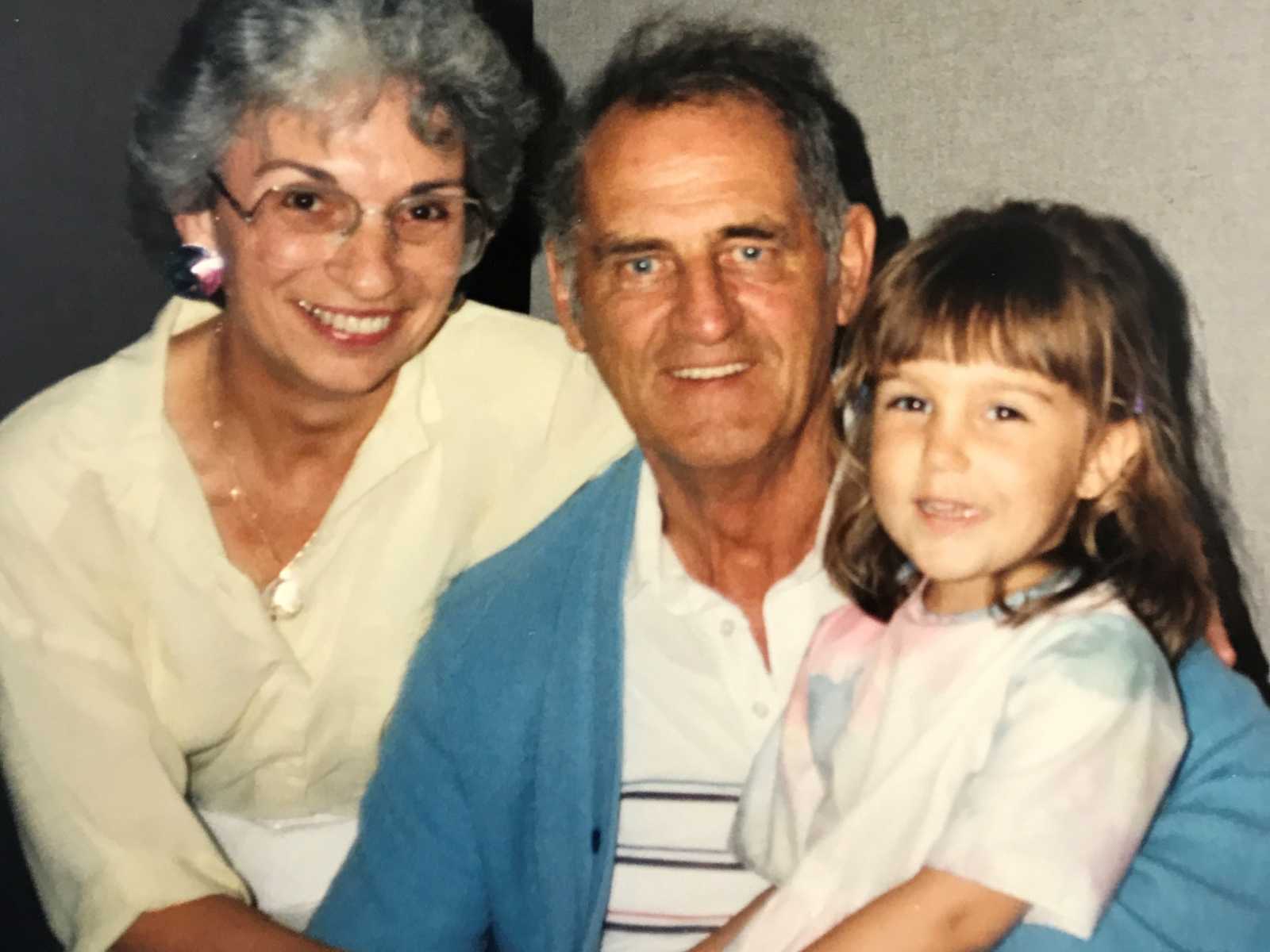 granddaughter sitting on grandfathers lap with grandmother next to them