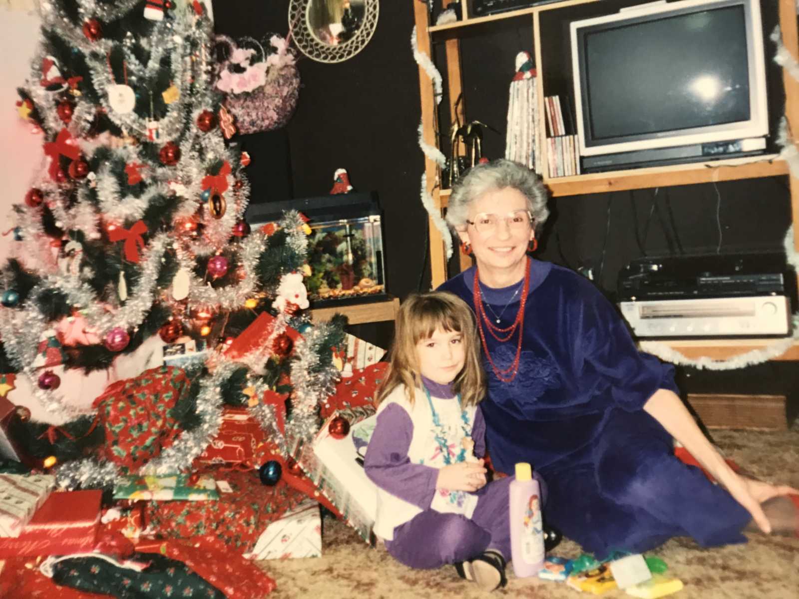grandmother and granddaughter on christmas morning sitting by tree and presents