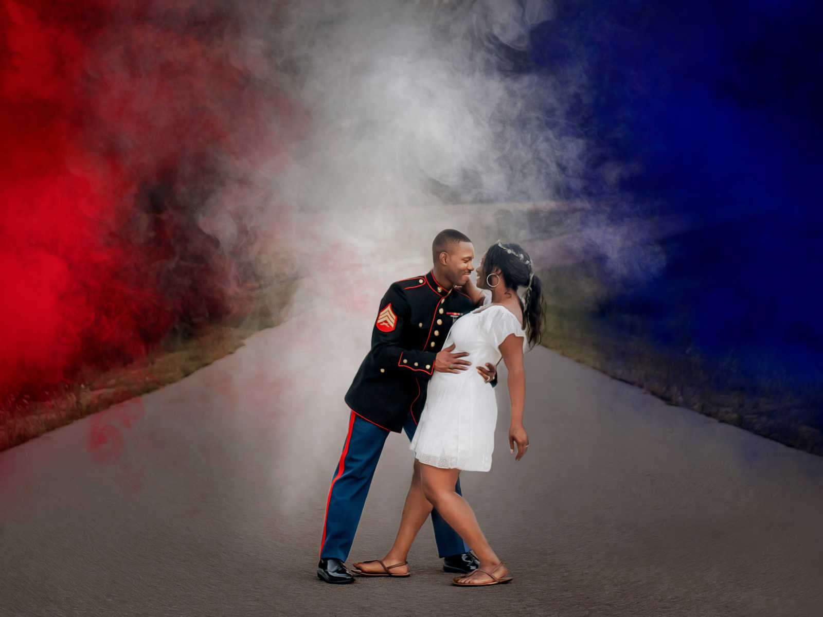 marine husband dips wife in middle of road with red white and blue smoke surrounding them 
