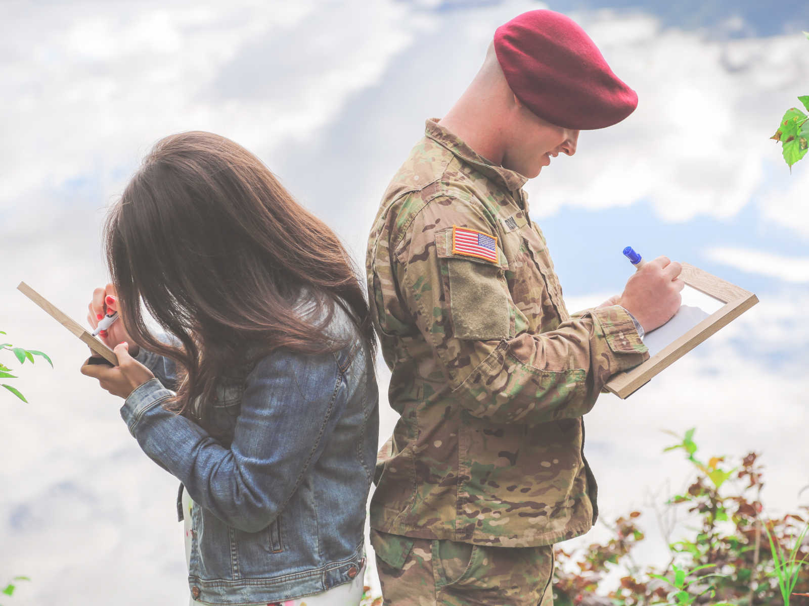 soldier and woman back to back writing on white boards