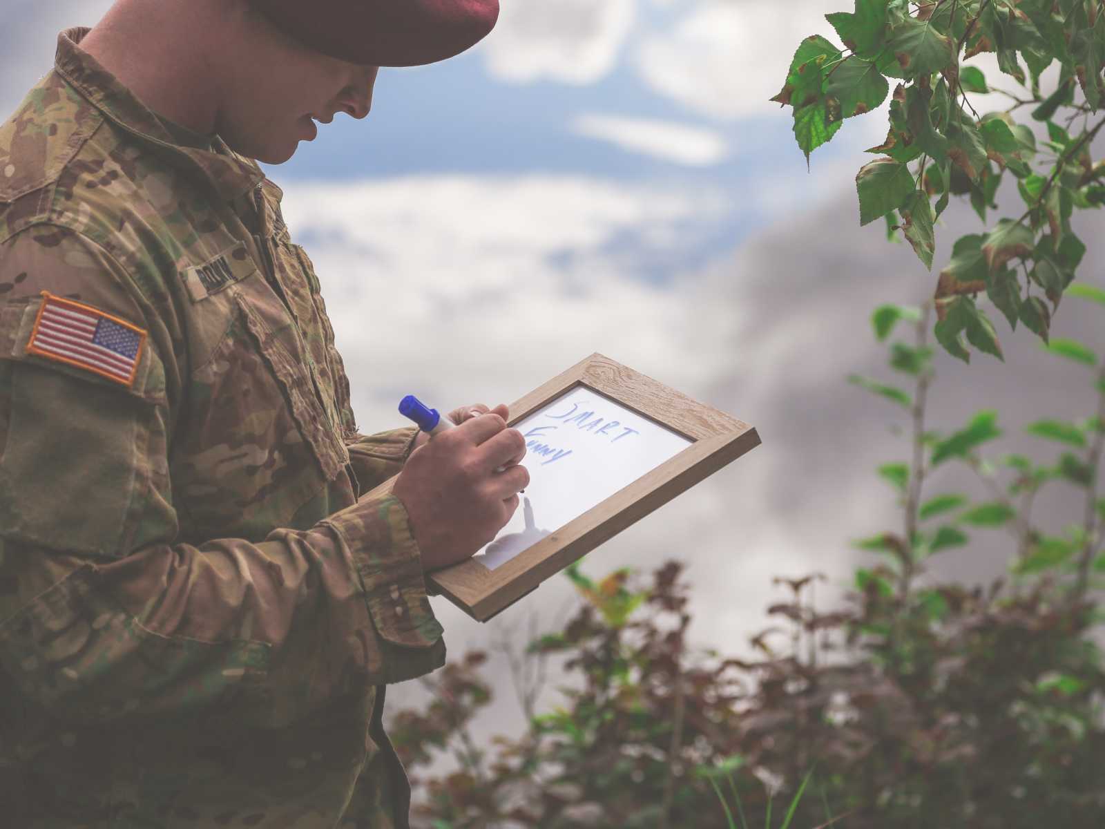 soldier writing on the white board with words "smart" and "funny" already written