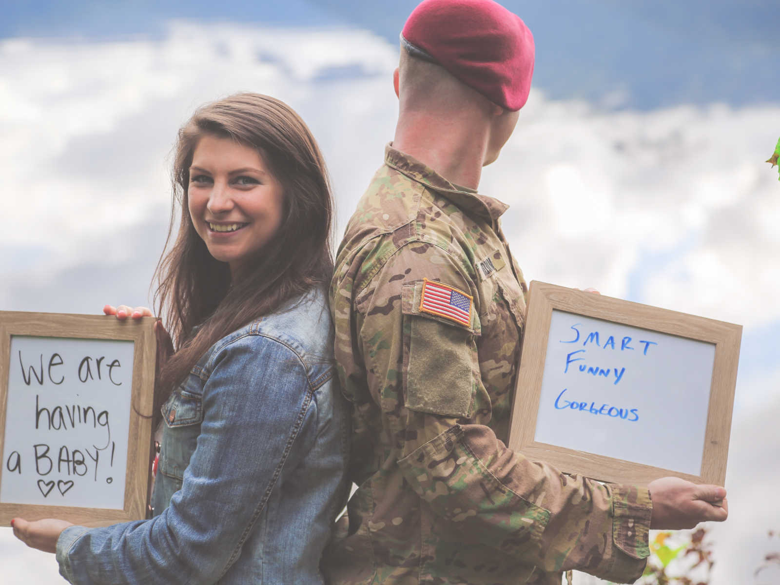 woman holding up white board that says, we are having a baby back to back with soldier holding white board and looking away