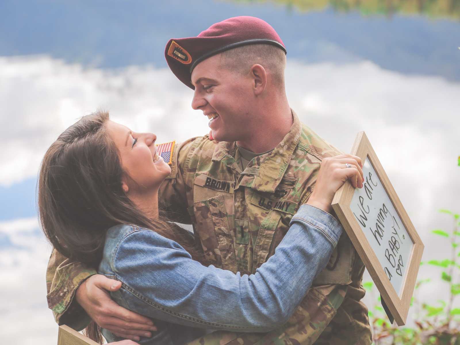 soldier and wife hug and smile at each other at news of having a baby