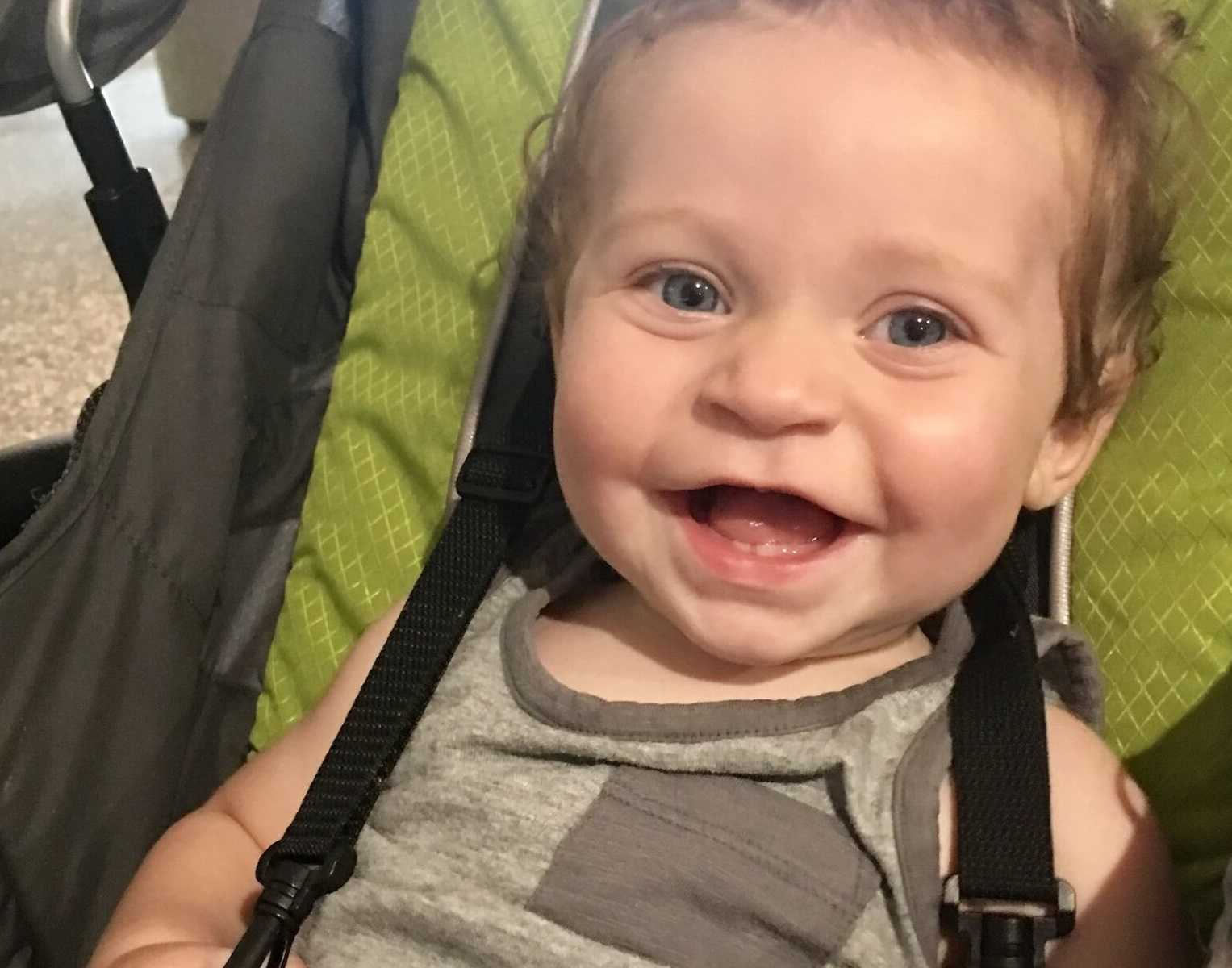 adopted toddler sitting in a stroller smiling