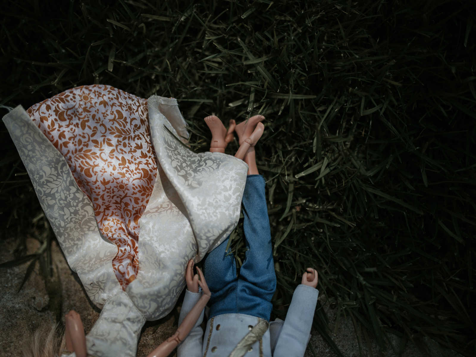 aerial view on ken and barbie holding hands while lying in the grass