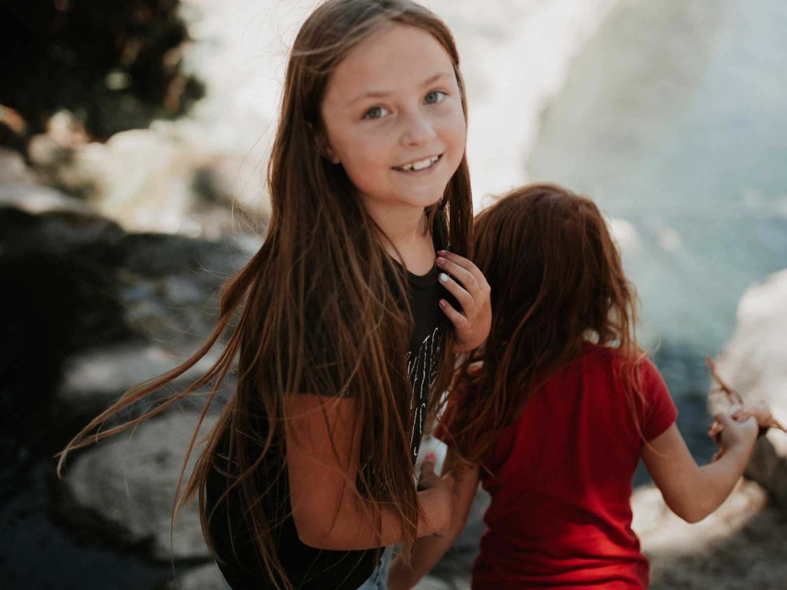 young girl looks back smiling with younger girl walking away in front of her