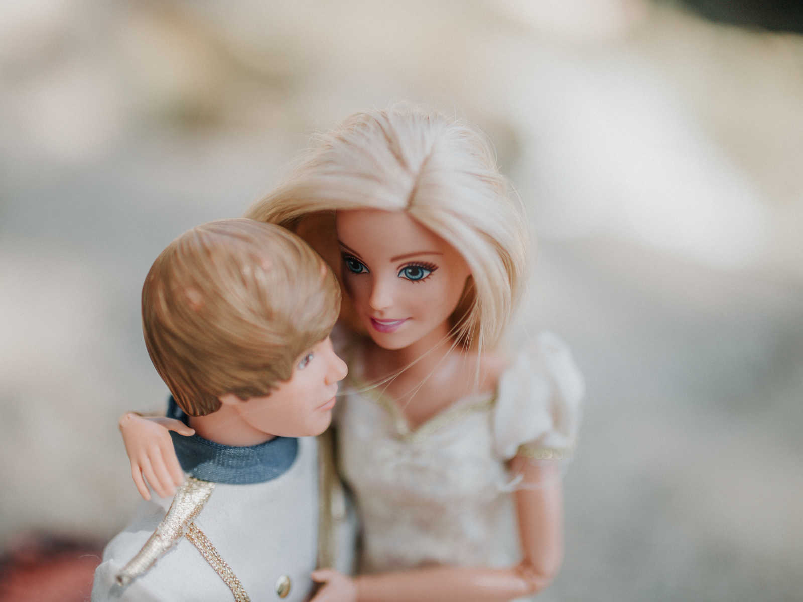 close up of barbie in white gown with arms wrapped around ken who is in prince outfit