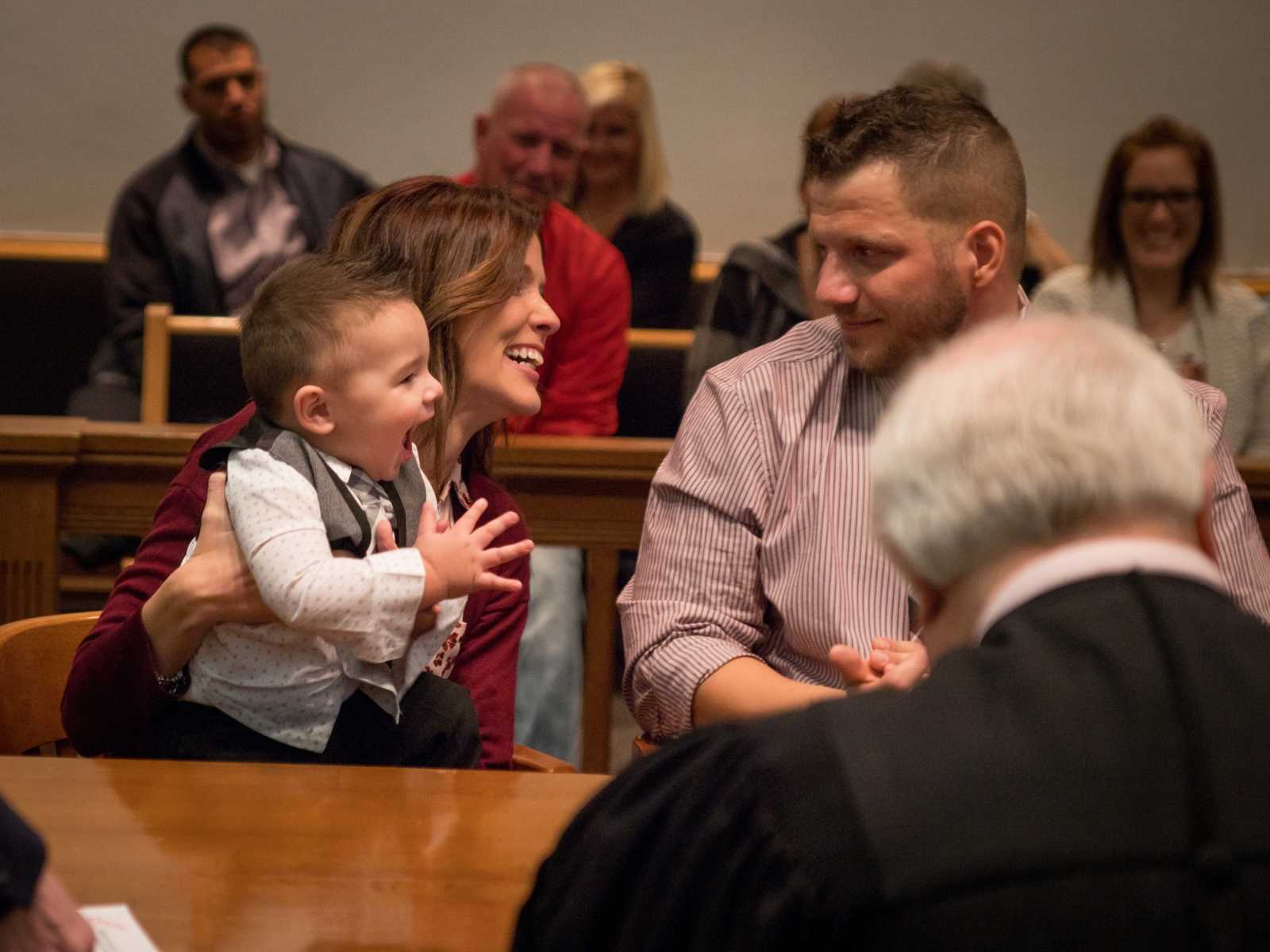 mother holds adoptive child as they all look at each other with excitement