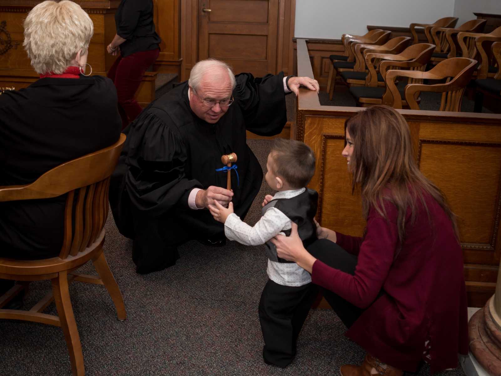 judge presents a gavel with a bow on it for adoptive son