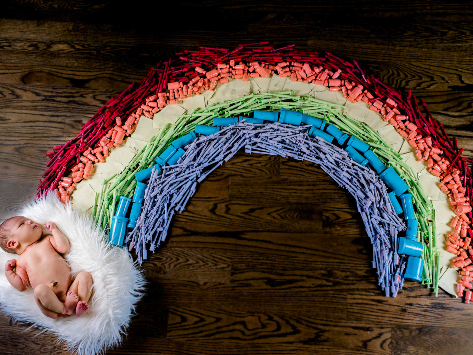 a rainbow display on hardwood floor with baby lying on the "cloud" at the end of the rainbow