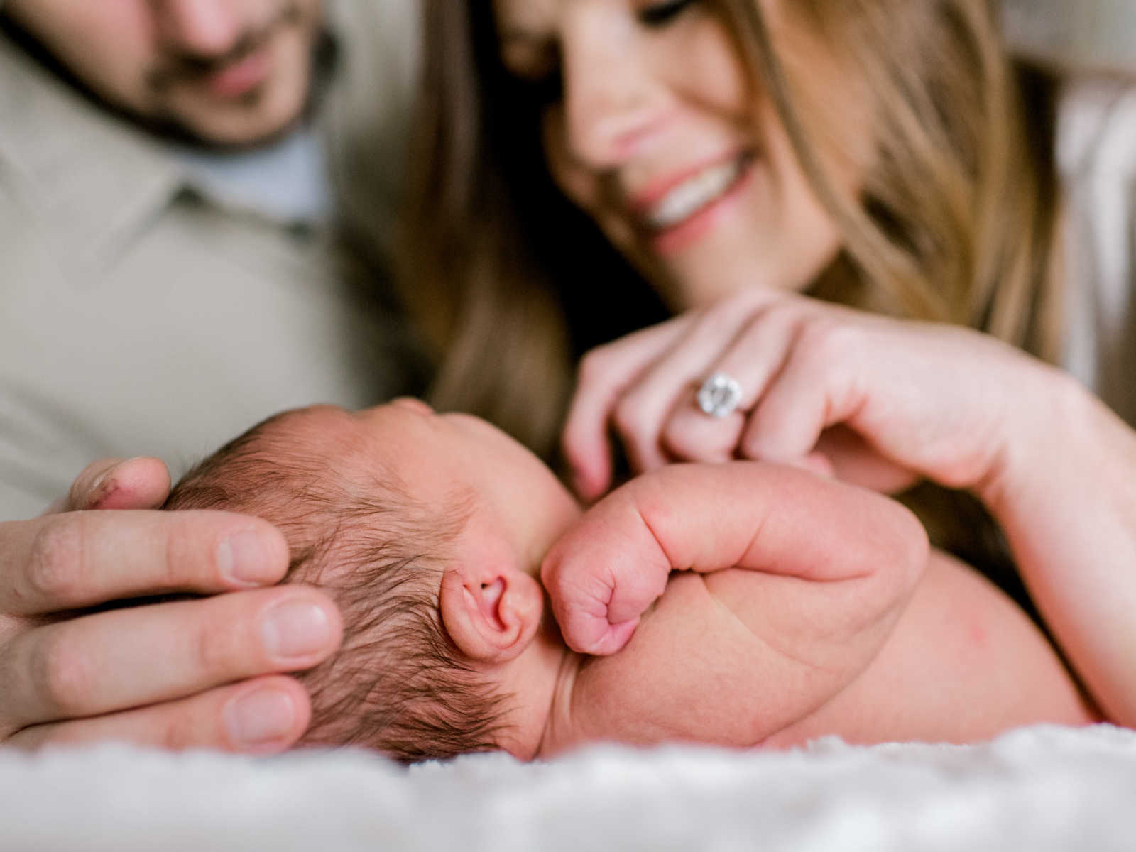 baby lying down while parents look on closely