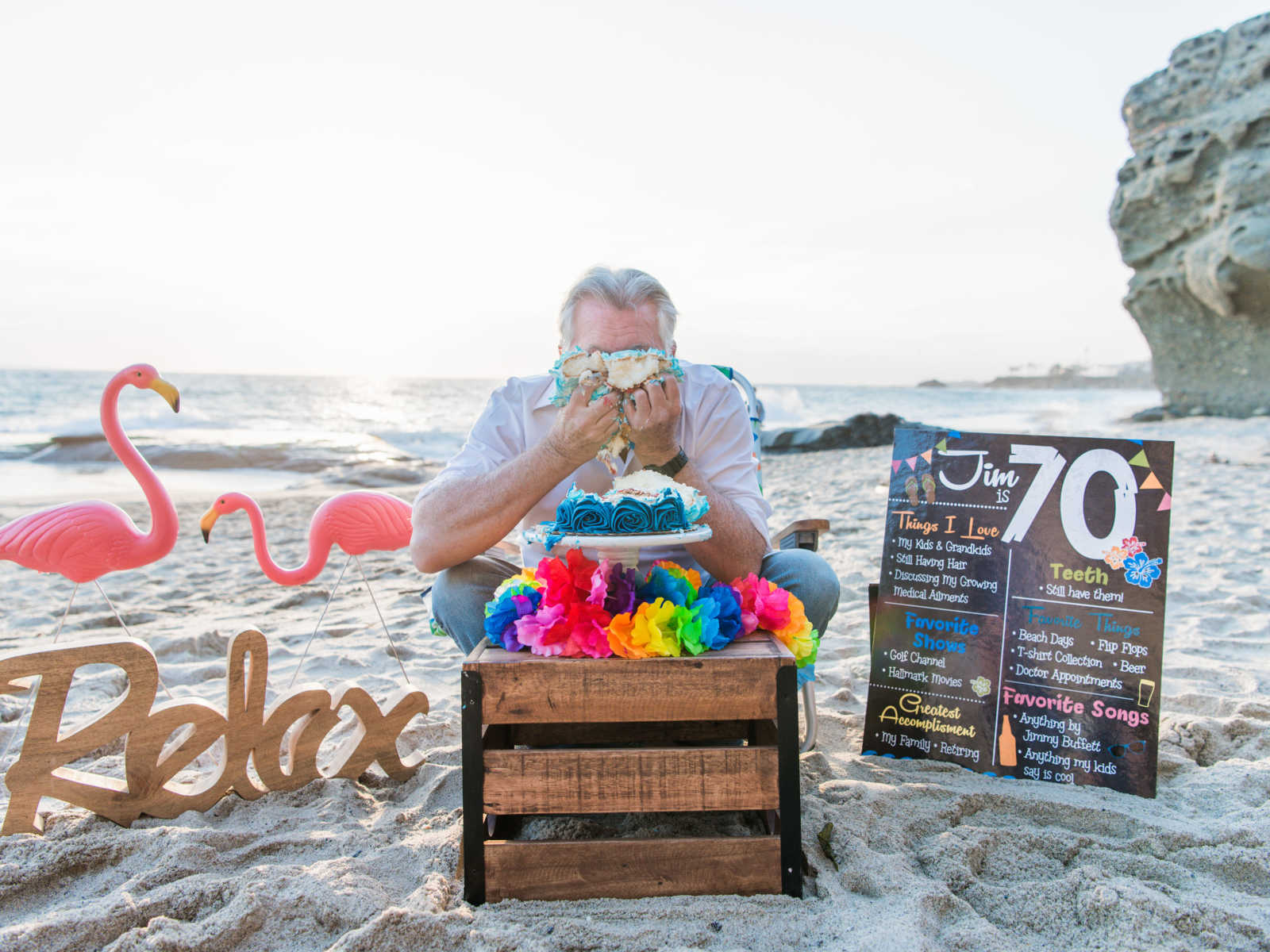 man shoves birthday cake all over his face on the beach