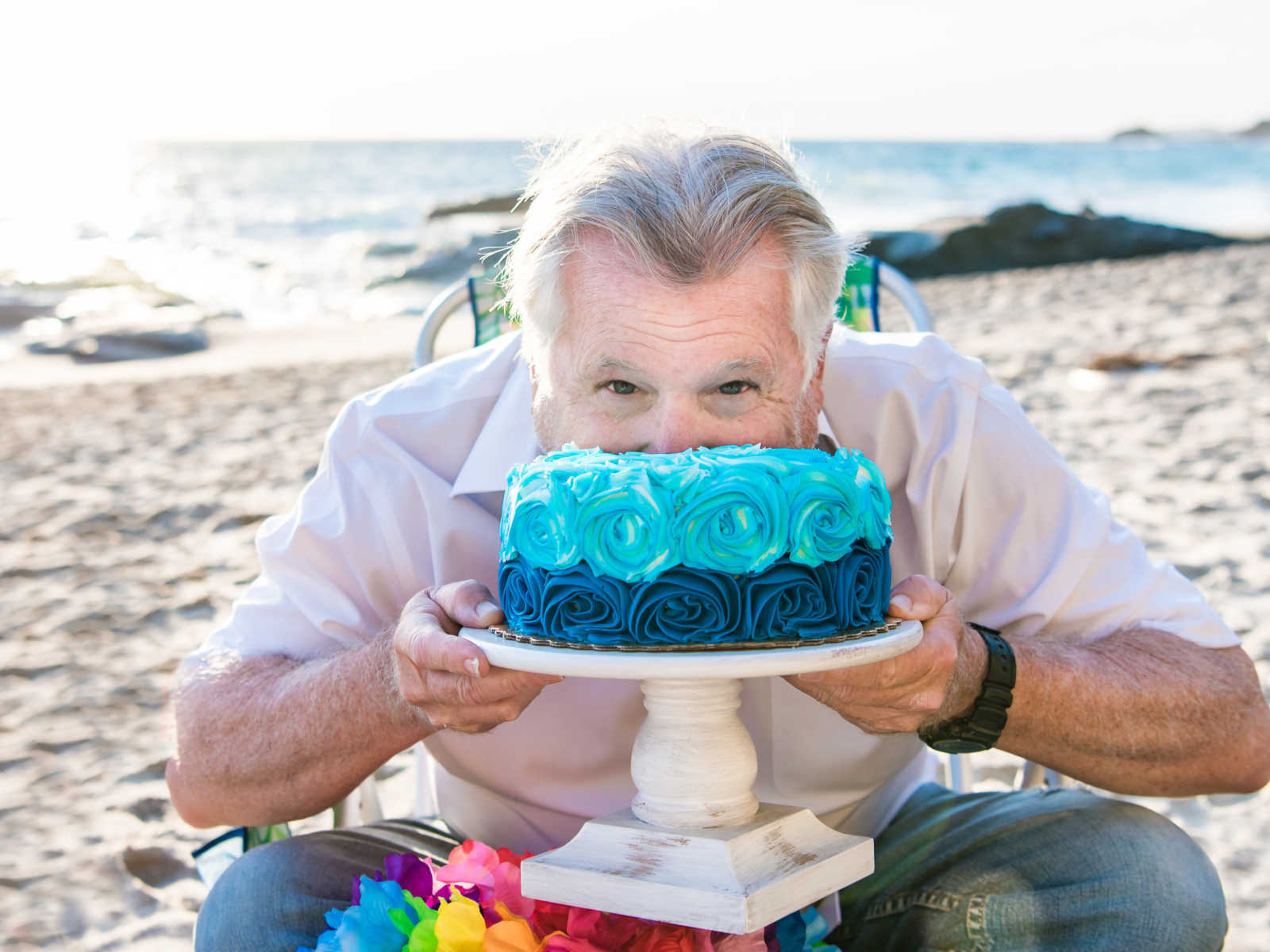 man shoving his face into his birthday cake on the beach