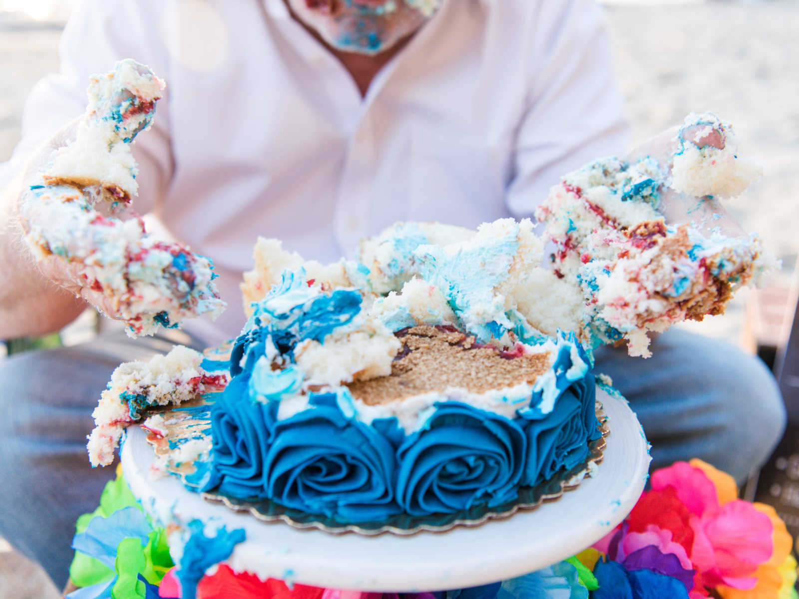 birthday cake is completely torn apart with mans body in the background