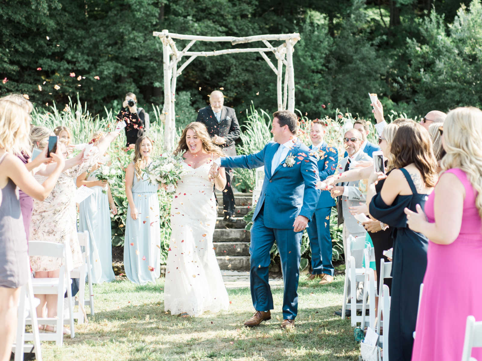 bride and groom walking down the aisle showered in flowers by guests