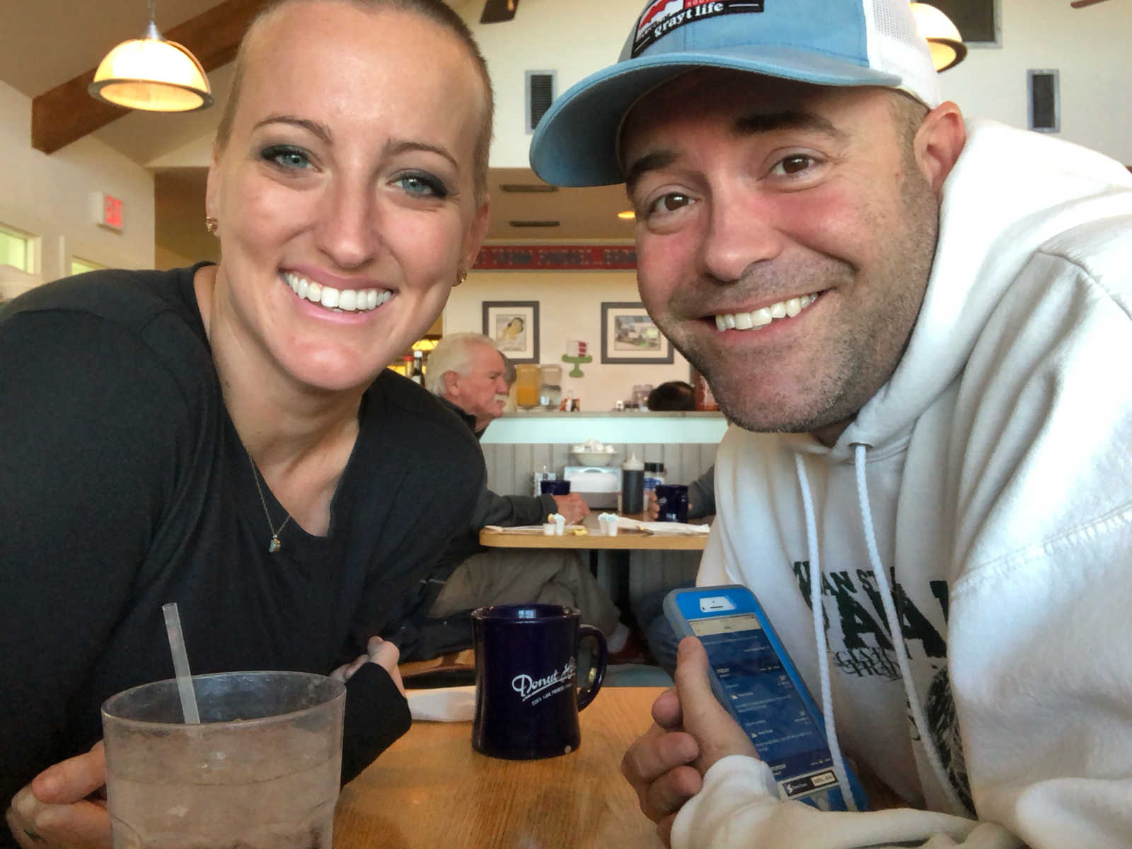 widower smiles at restaurant table across from boyfriend in selfie