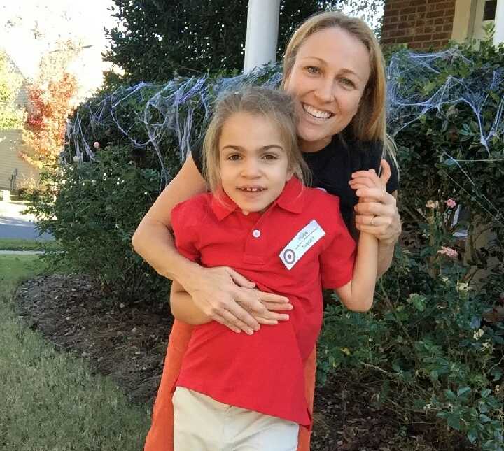 mother smiles whiles holding terminally ill daughter who is wearing target uniform and name tag