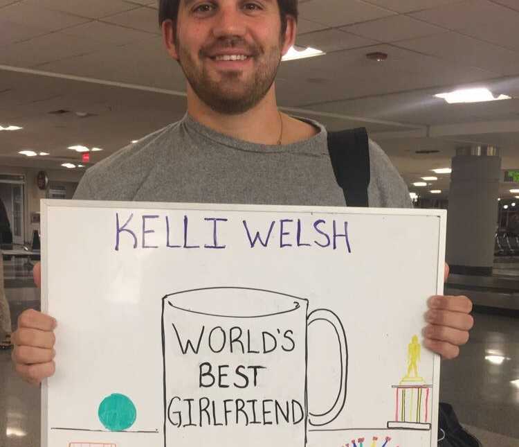 boyfriend greets girlfriend with hand-drawn "world's best girlfriend" sign at airport