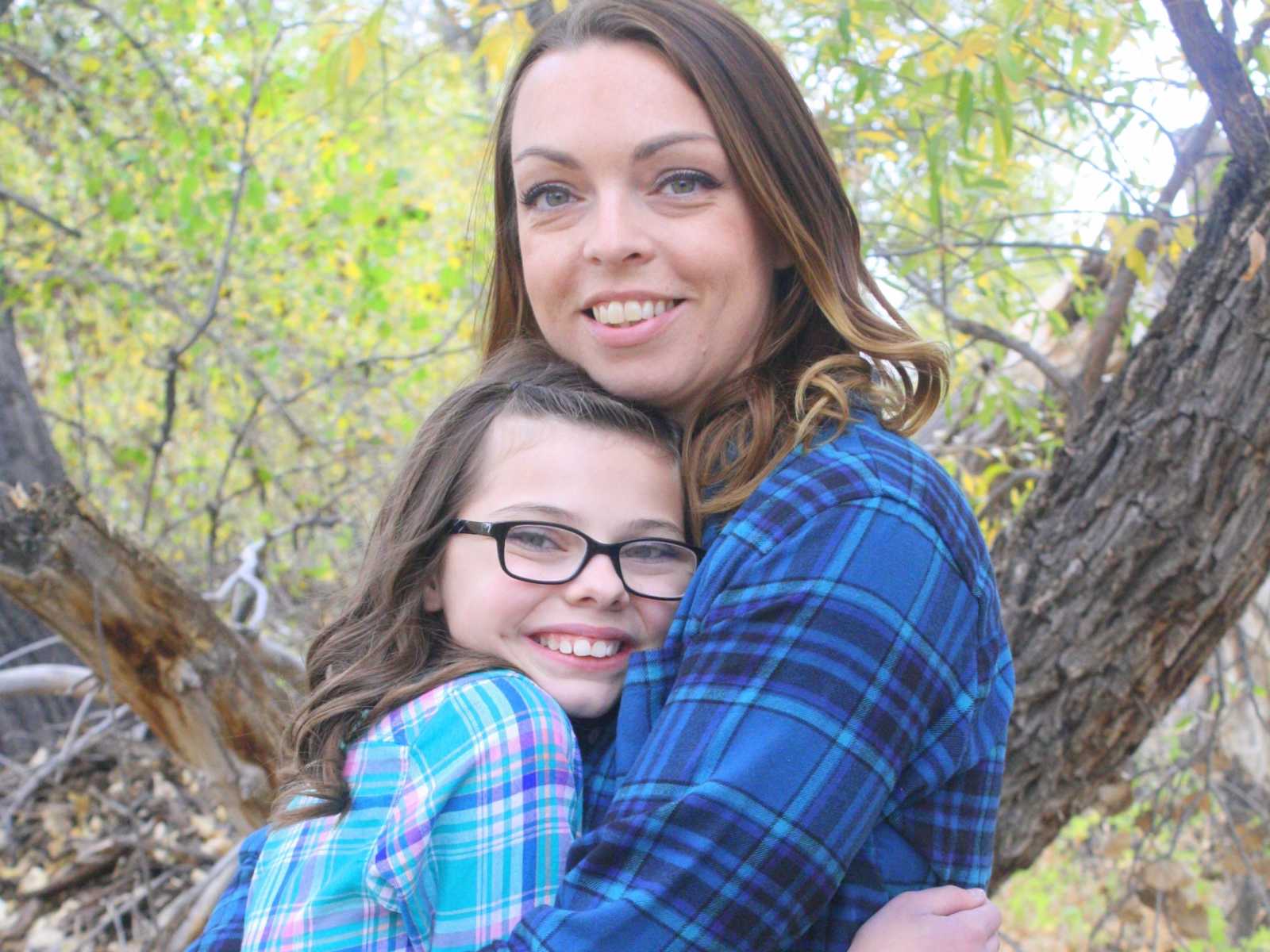 mother hugs adoptive daughter in the woods