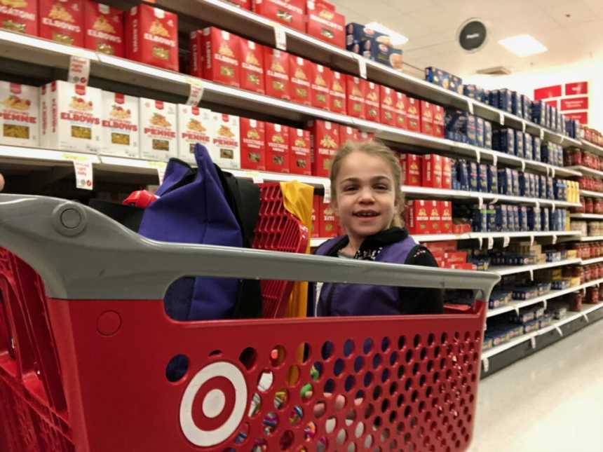 young woman smiles while sitting in target shopping cart in pasta aisle