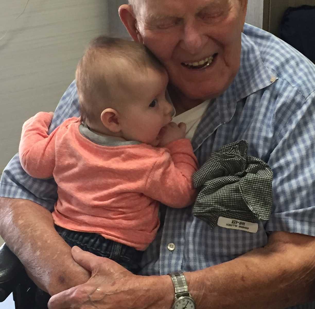 oldest man in Canada hugs baby great-great-grandson to chest while smiling in wheel chair