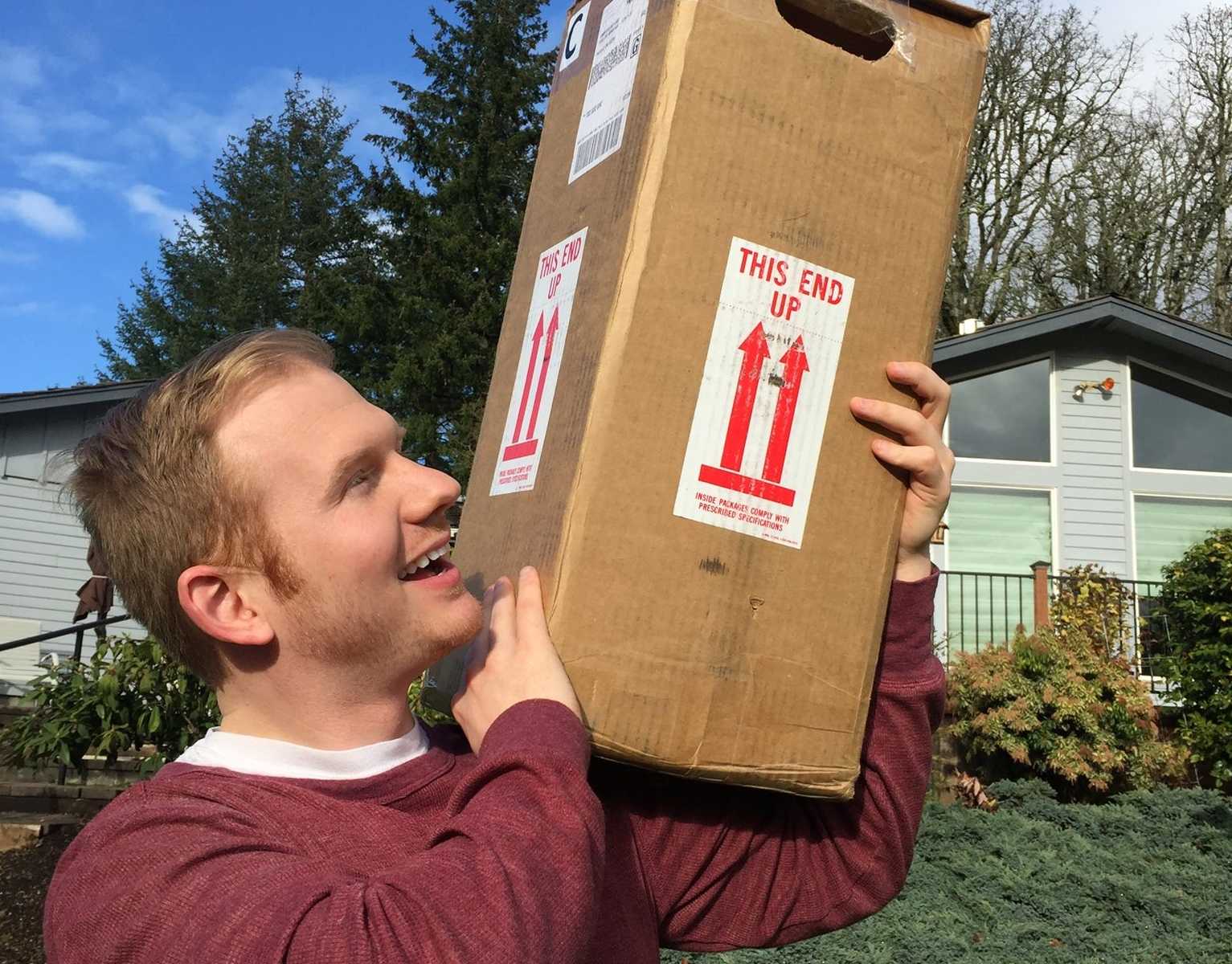 man holding box of embryos over his shoulders and smiling up at it