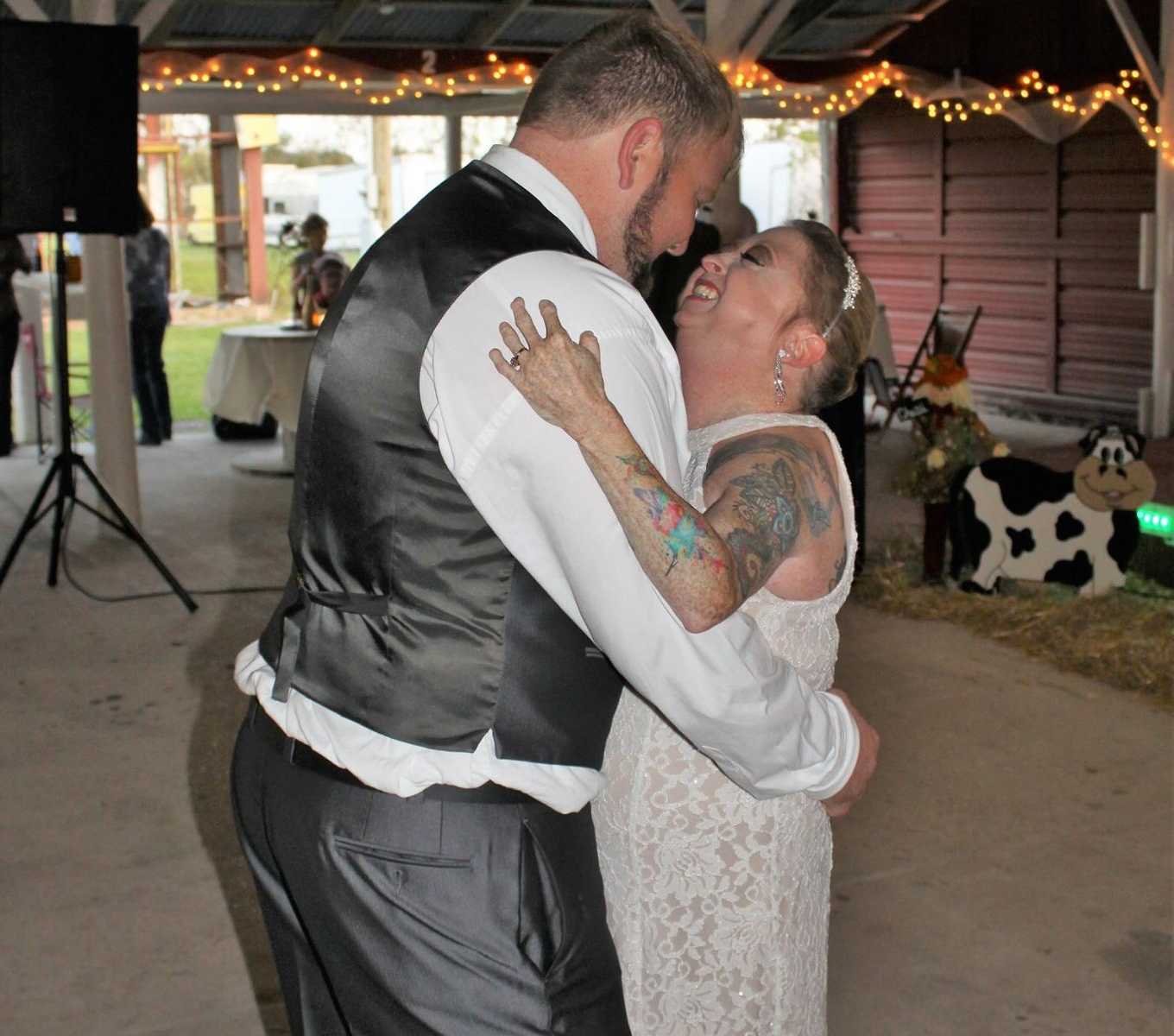 disabled couple holding each other close while smiling at each other at wedding with speakers in background
