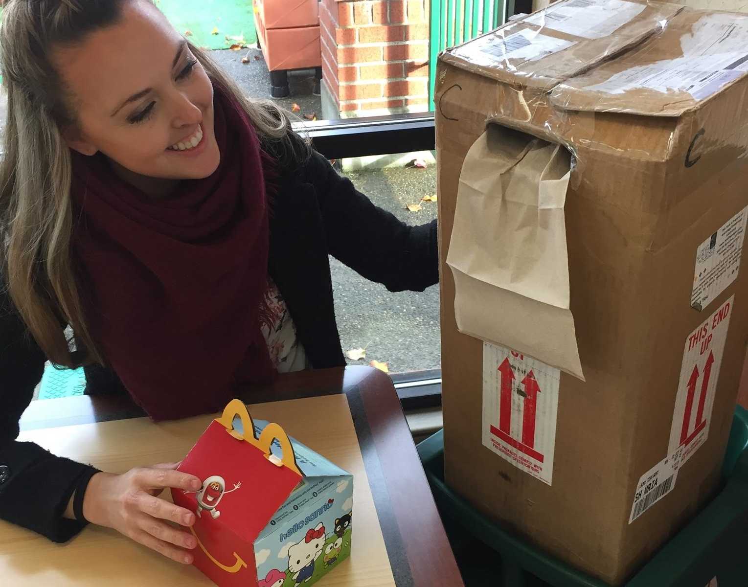 woman smiling at box of embryos with a happy meal in front of it