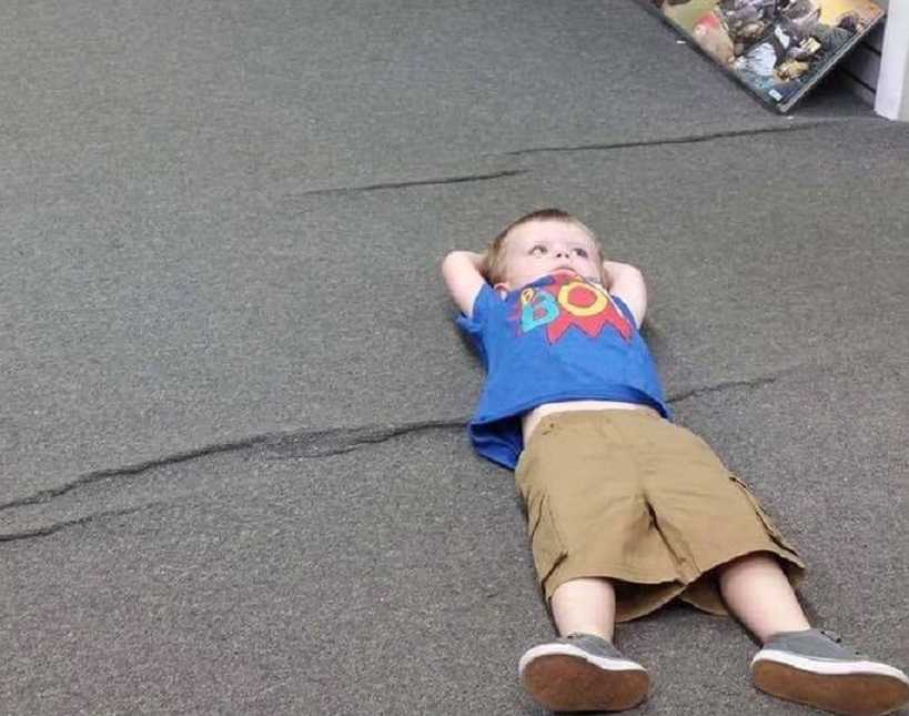 Toddler lies on his back with arms behind his head