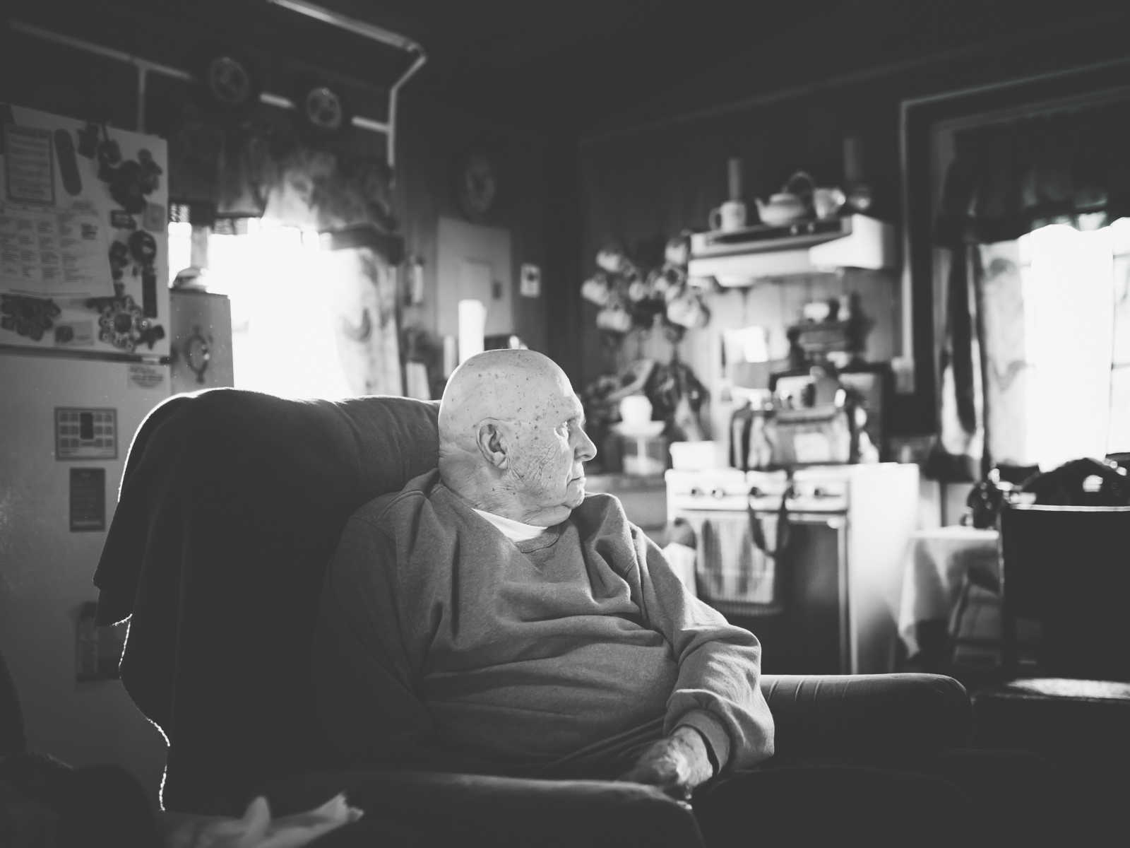 elderly man sitting in his chair looking into the distance