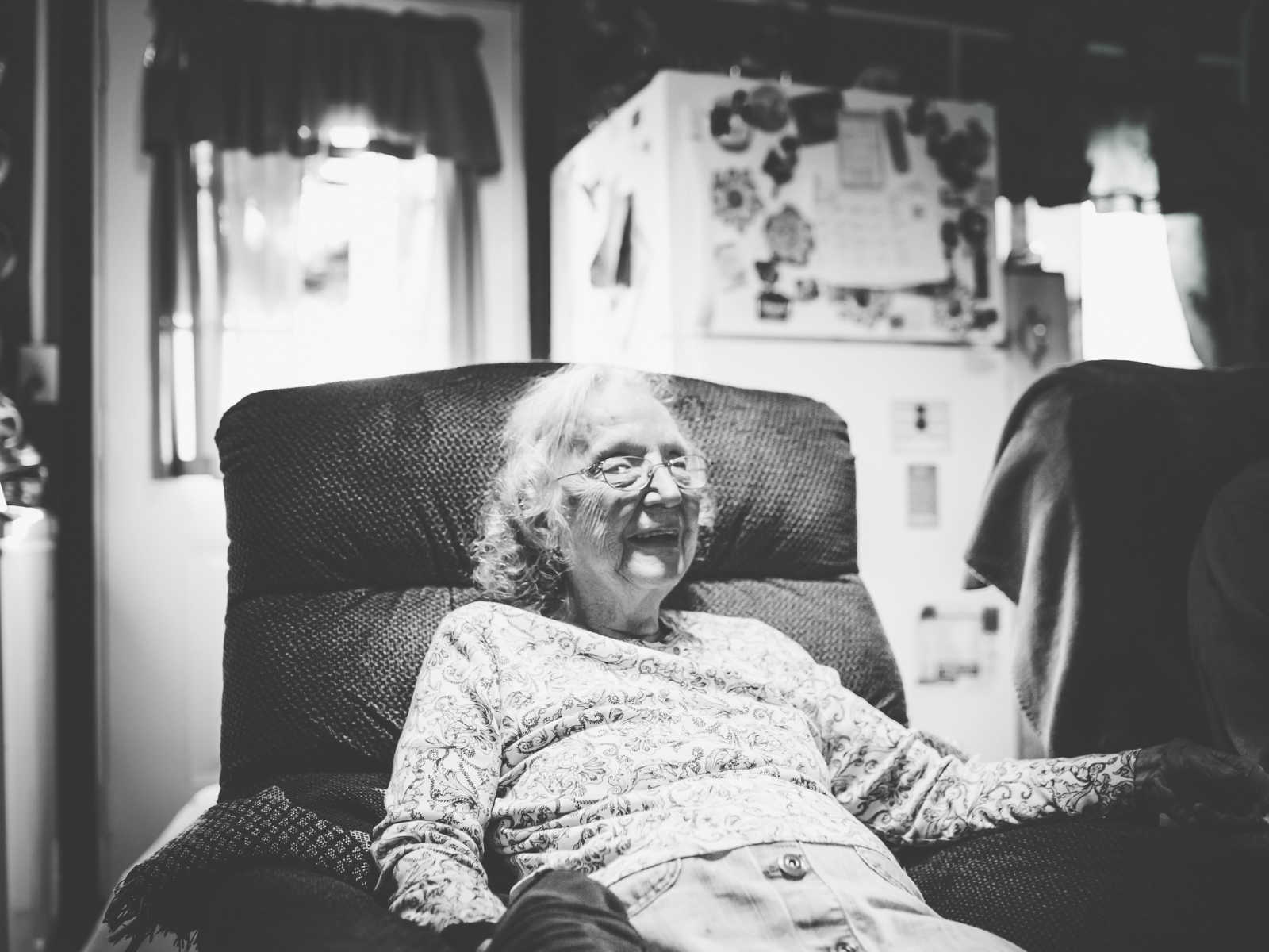 elderly woman smiles in chair in her home