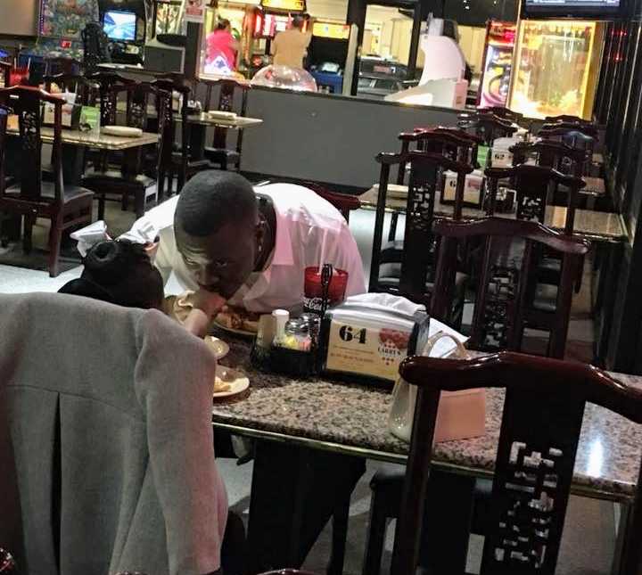 daughter holds out hand across dinner table at restaurant for father to kiss