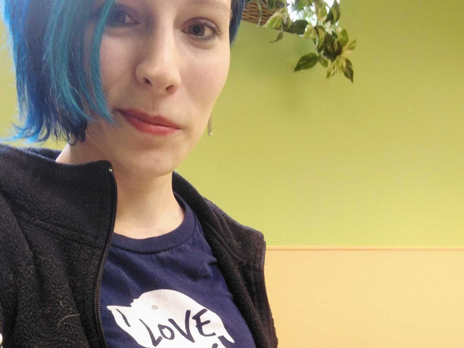 Doggy daycare worker with short blue hair smirks in her selfie