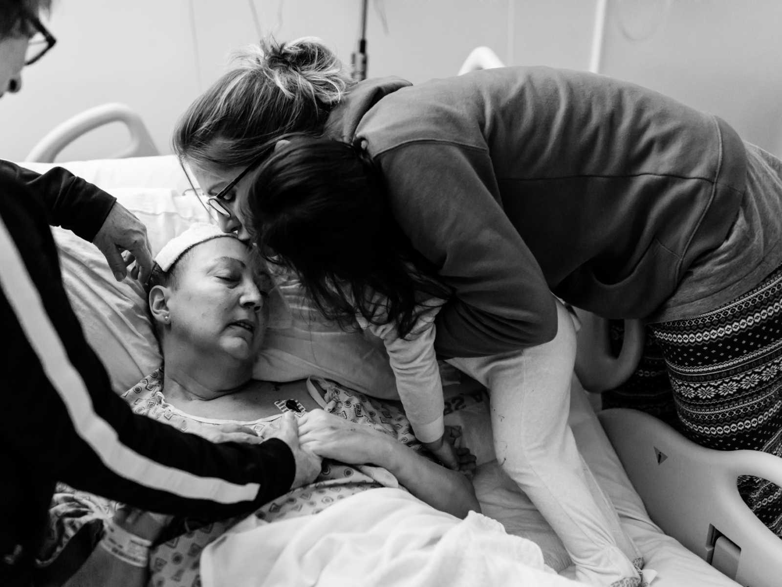 Woman with non-hodgkin's lymphoma receives kiss on forehead from sister who is holding toddler 