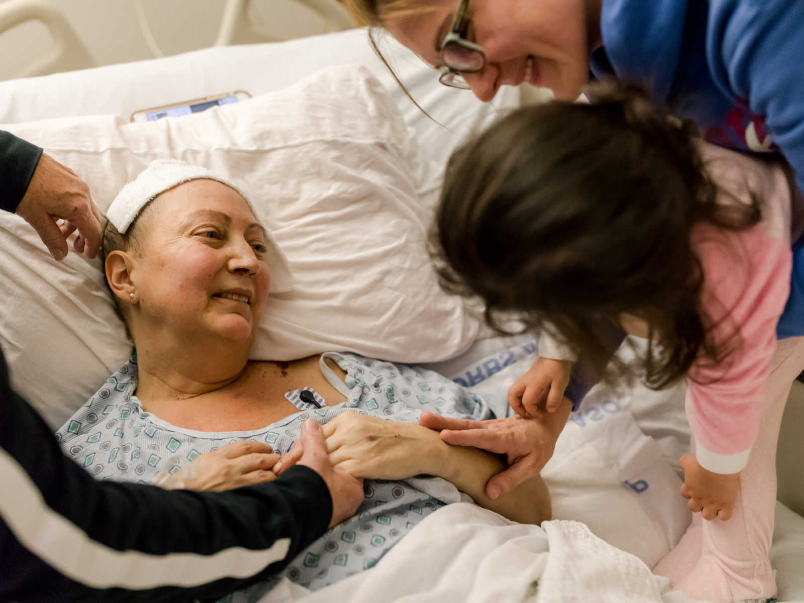 Non-hodgkin's lymphoma patient smiles up at toddler who is being help in the arms of patients sister