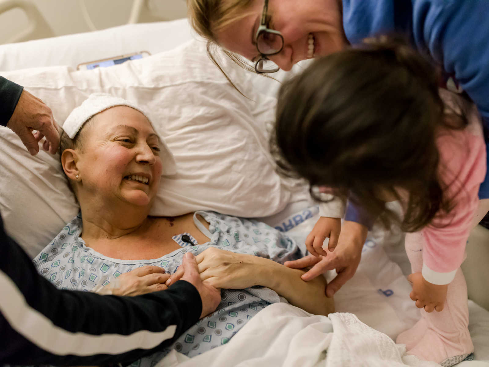 Non-hodgkin's lymphoma patient laughs at toddler who is being held by patients sister