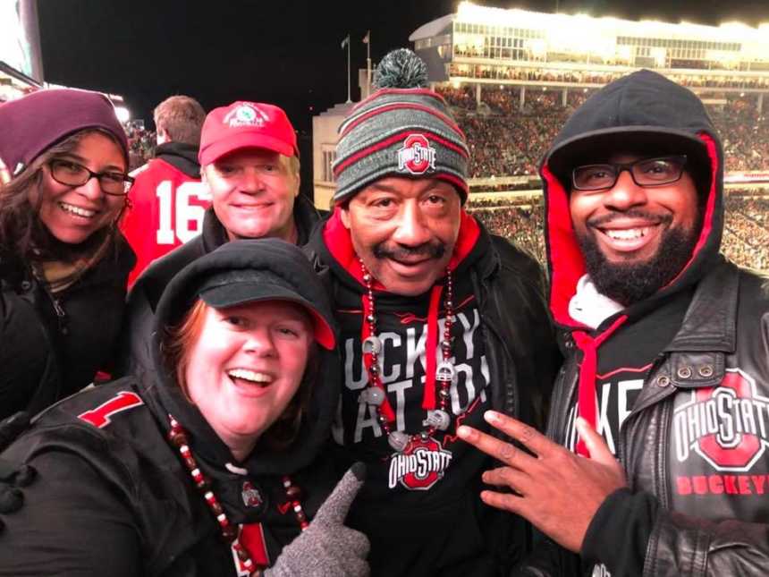 five people smiling in ohio state gear in packed football stadium