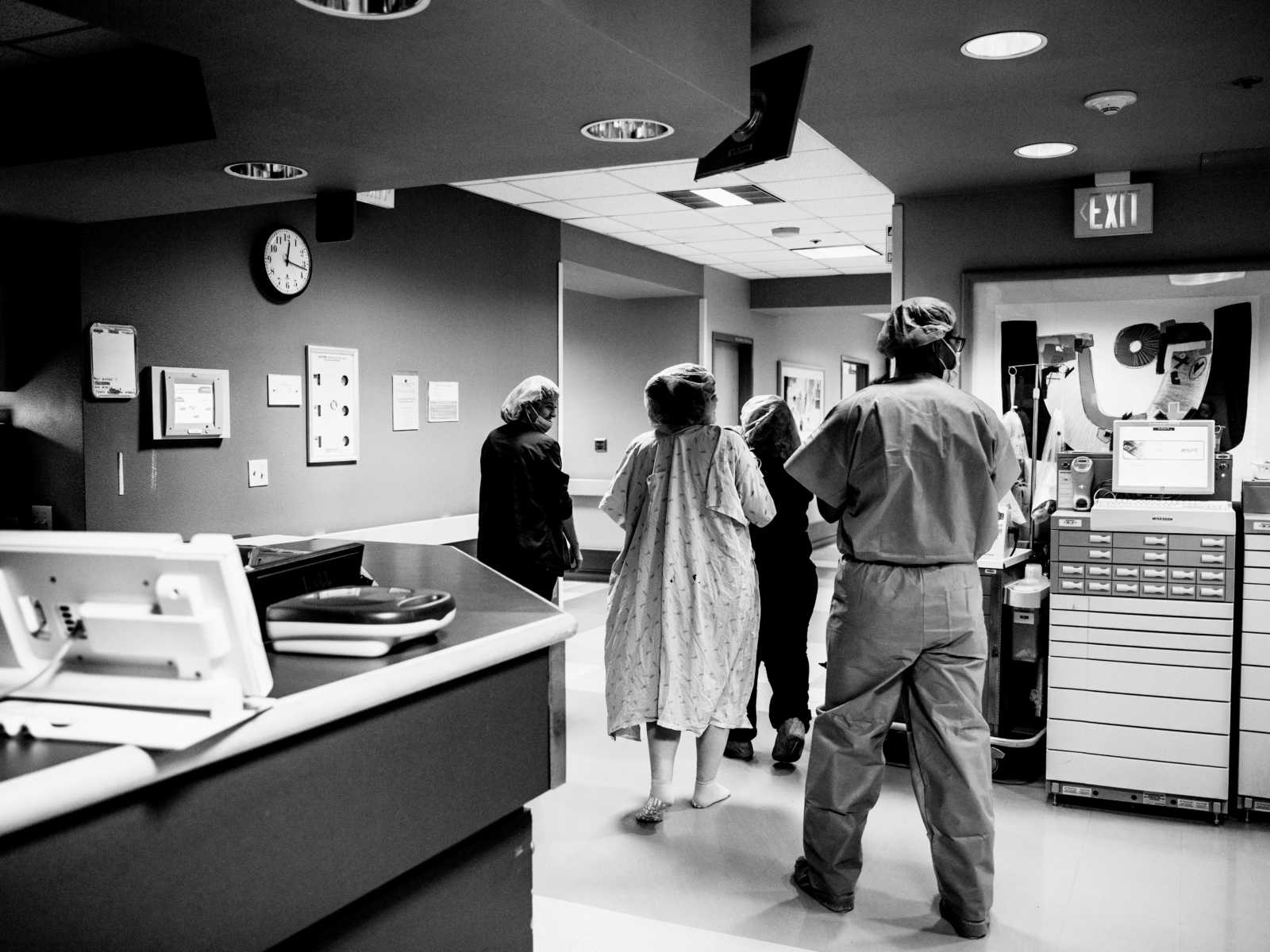 Marine walking down hospital hallway behind pregnant friend and nurses